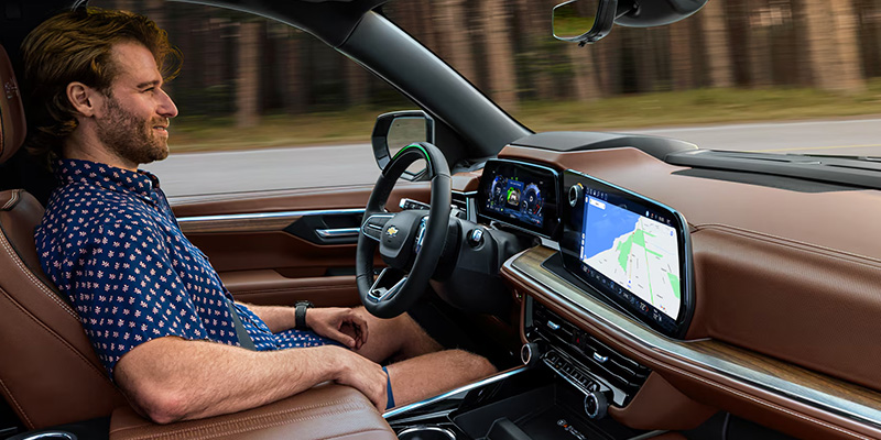 A man sitting in the driver's seat of a Chevrolet with a touchscreen displaying a map