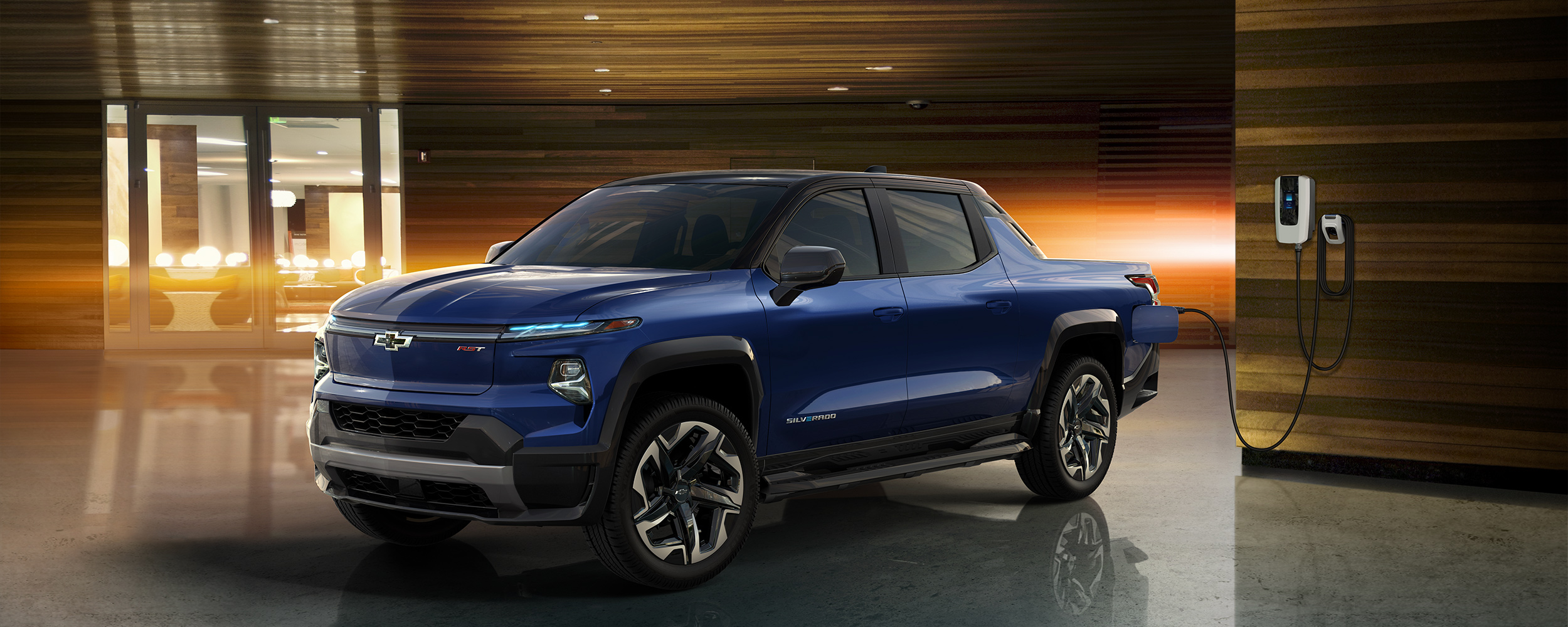 A Chevrolet Silverado EV electric truck charging indoors near a modern wall