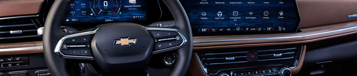 The steering wheel and infotainment system of the 2025 Chevrolet Suburban in Benton, AR